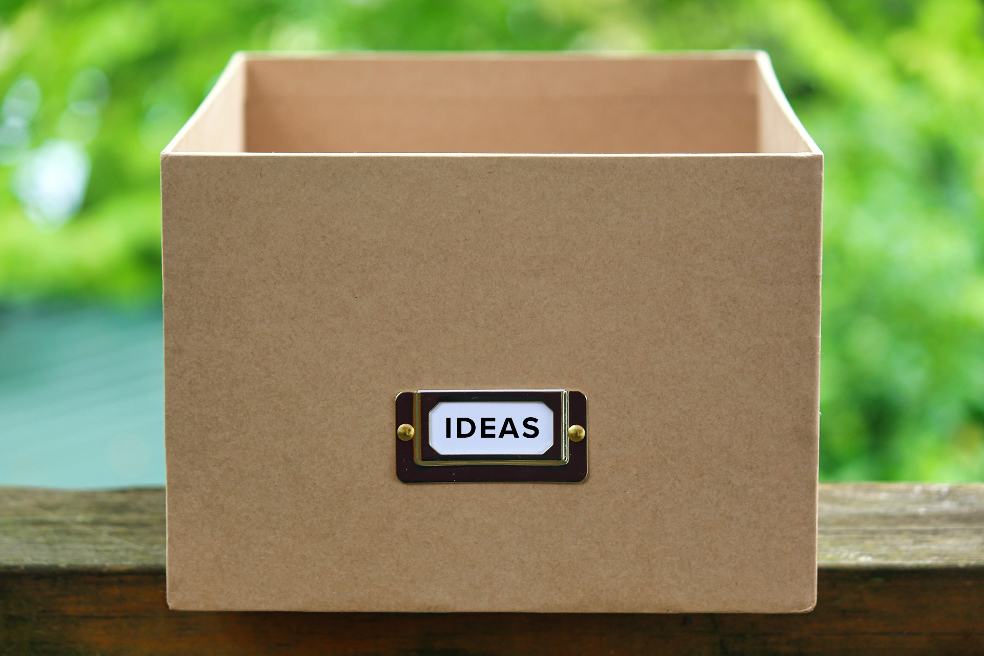 idea box on a wooden table with greenery in the background