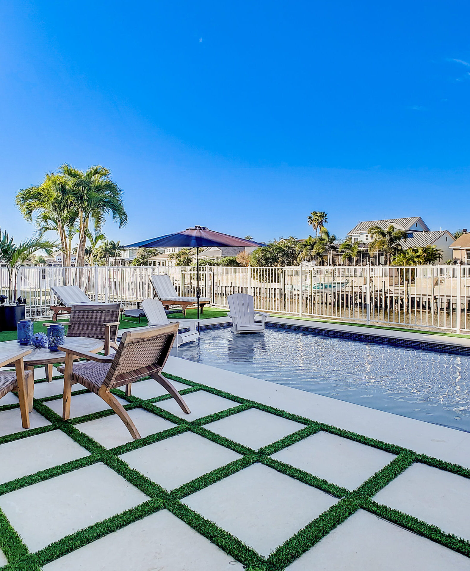 Luxurious and modern backyard pool on a waterfront canal with palm trees and homes in the background