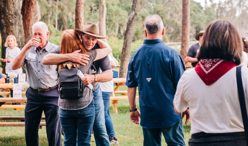 Dewey Mitchell hugging real estate agent at Fall Fun Fest with others walking in background